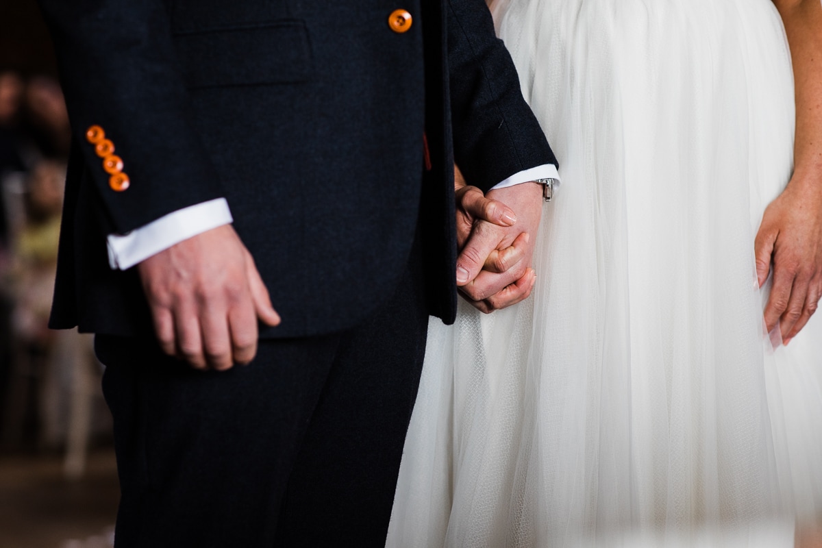 bride and groom hold hands during ceremony