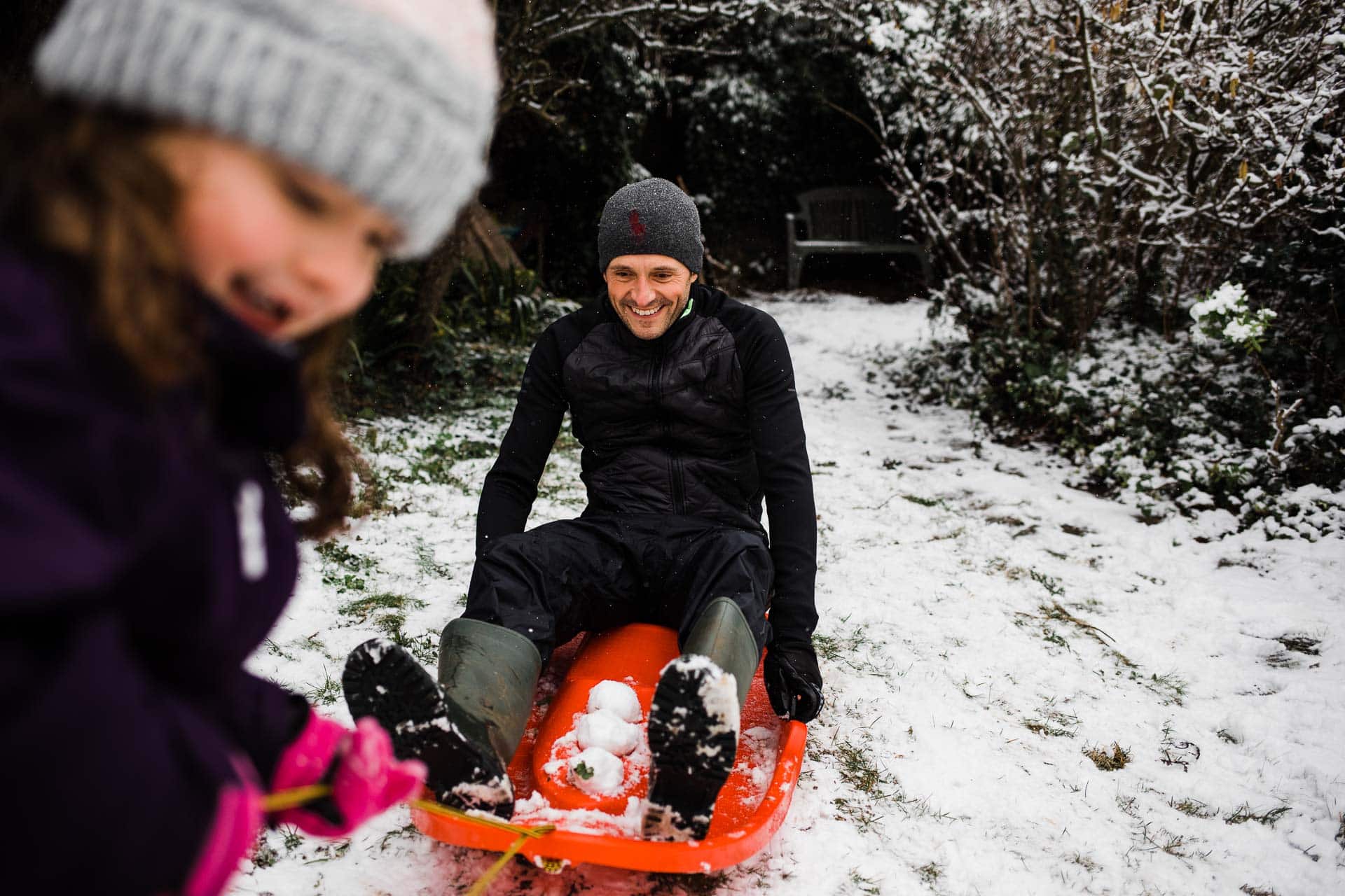 little girl pulls daddy on sledge